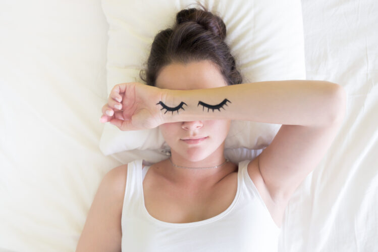 Painted sleeping eyes and Attractive brunette young woman in the white bed at morning time